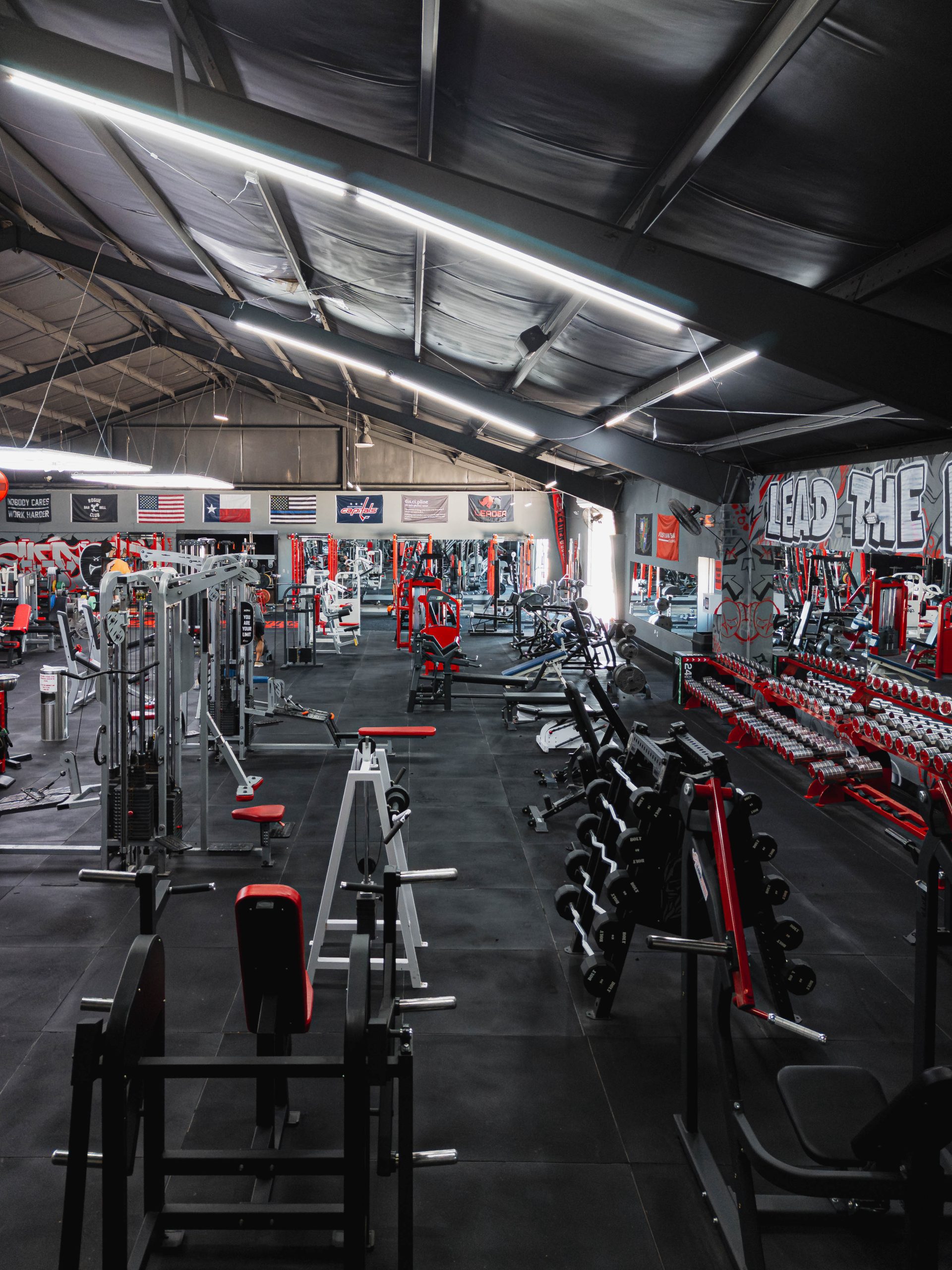 Leader Fitness free-weight area with dumbbell racks and wall murals